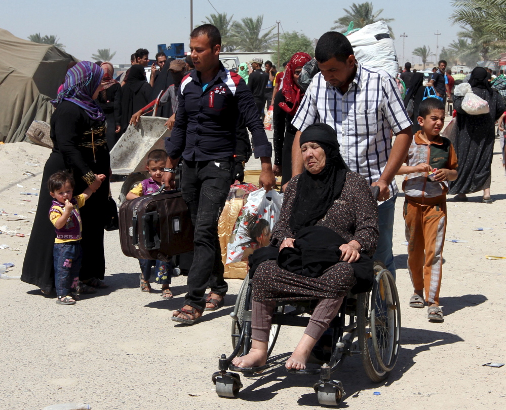 A displaced Iraqi Sunni man pushes an elderly woman in a wheelchair on the outskirts of Baghdad Sunday after the Islamic State overran one of the last remaining districts held by government forces in the city of Ramadi.