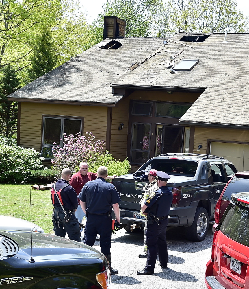 Homeowner Sean Crothers, in red T-shirt,  chats with Falmouth fire and police officials at the scene Monday.
Gordon Chibroski/Staff Photographer
