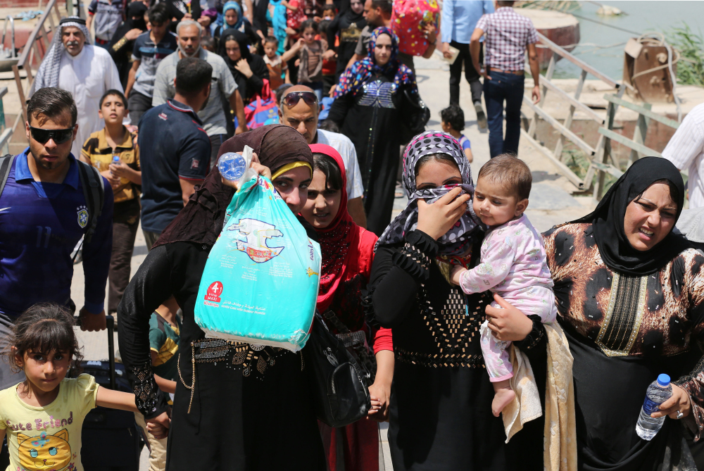 Displaced Iraqis cross the Bzebiz bridge to flee fighting in Ramadi on Wednesday. Thousands of displaced people fleeing violence in nearby Anbar province poured into Baghdad province Wednesday after the central government granted them conditional entry, said a provincial official.