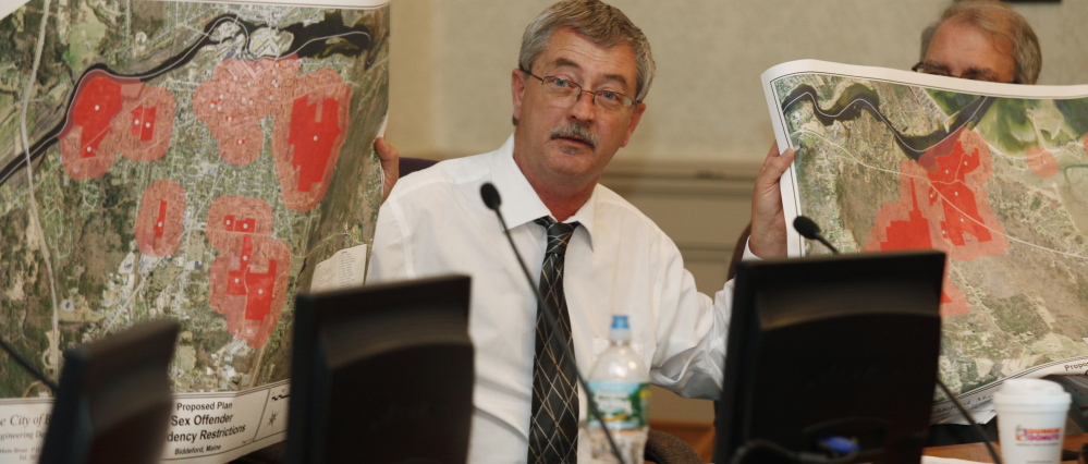 Biddeford City Councilor John McCurry Jr. holds up two maps showing areas that would be affected by proposed residency restrictions for registered sex offenders.