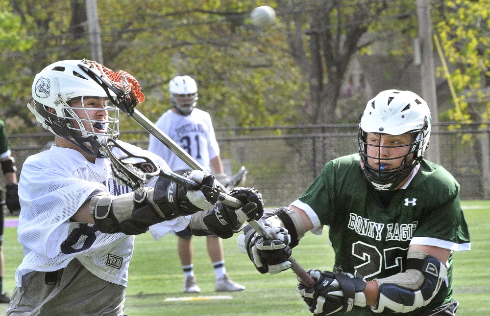 Zack Klein of Bonny Eagle, right, tries to block a shot on goal by Robert Nolan of Portland during Portland’s 15-6 victory Wednesday in a schoolboy lacrosse game at Deering High.