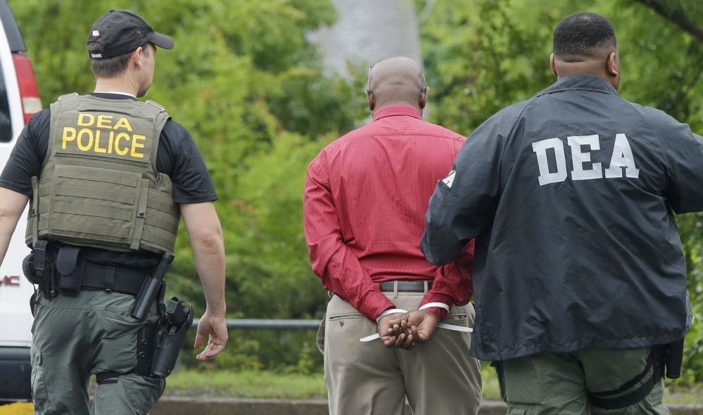 An unidentified man, center, is escorted from a medical clinic in Little Rock, Ark., by Drug Enforcement Administration officers on Wednesday.