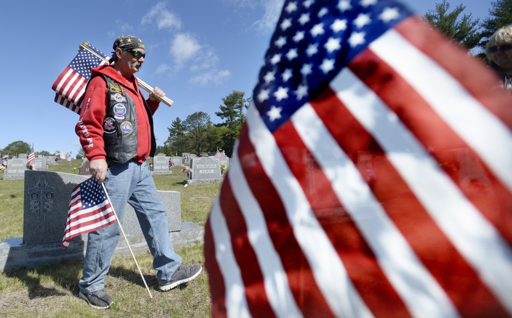 Carl Ravida of Biddeford, who is a Vietnam veteran and a member of Vietnam Veterans of America Chapter 1044, places flags on veterans' graves for Memorial Day. Shawn Patrick Ouellette/Staff Photographer