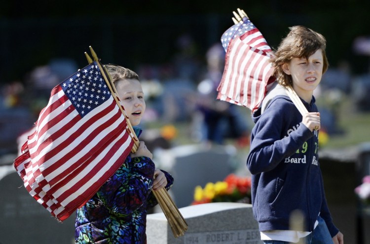 Carly Belanger 9, and Travis Belanger 13, both of Saco, look for veterans' graves to put flags on at St. Ignatius Cemetery in Sanford on Saturday.  Shawn Patrick Ouellette/Staff Photographer