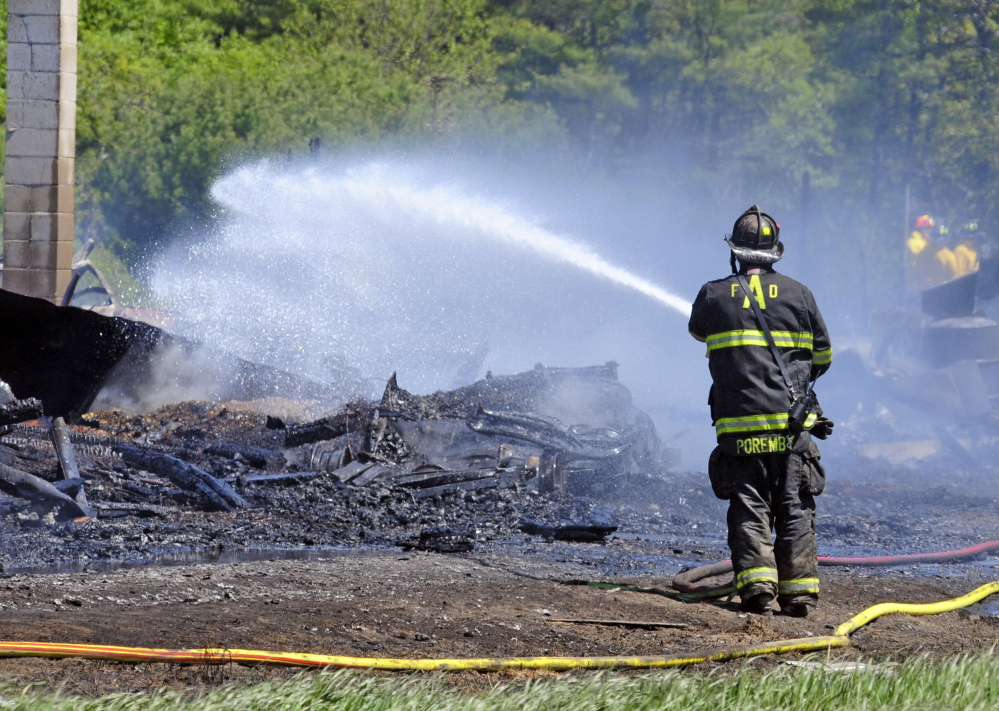 Firefighters extinguish any remaining hot spots after a fire destroyed a chicken barn Saturday in Pittston. Joe Phelan/Kennebec Journal