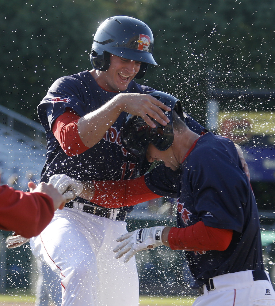 Jonathan Roof, left, and Jantzen Witte are doused with water by teammates after Witte was hit by a pitch with the bases loaded in the bottom of the seventh inning, forcing home Roof with the deciding run.
