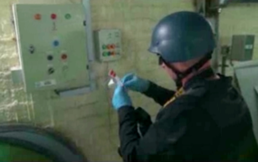 This file image made from video broadcast on Syrian State Television purports to show an expert taking samples at a chemical weapons plant at an unknown location in Syria. 