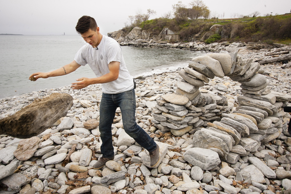 Daniel Morales-Walsh, 25, of South Portland, tosses aside a log he used as a form to create an arch at Fort Williams Park in Cape Elizabeth.