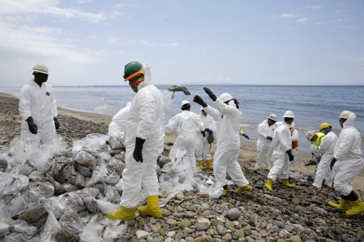 Workers gather oil-contaminated sand bags at Refugio State Beach, north of Goleta, Calif.