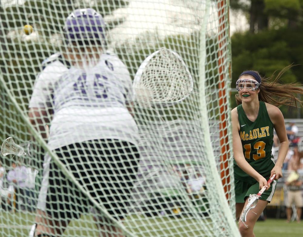 Molly Barr of McAuley watches her shot head toward the goal in the second half Monday as Evelyn Molina guards the net for Deering. McAuley rallied for a 13-12 victory.