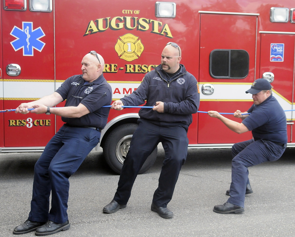 Augusta Fire Department paramedics Randy Gordon, left, Jeremy Manzer and Kurt Gordon get pulled inside Hartford Fire Station in Augusta by colleagues during rescue training.