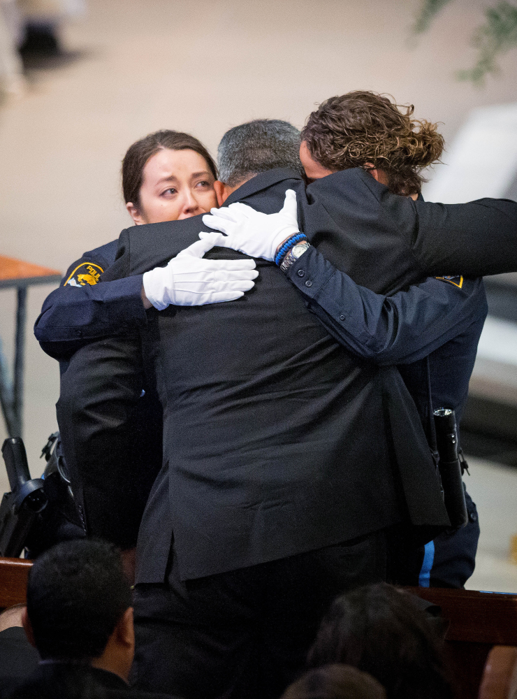 Two Omaha police officers embrace Hector Orozco, the husband of Kerrie Orozco, who was slain when she answered the call to help another officer.