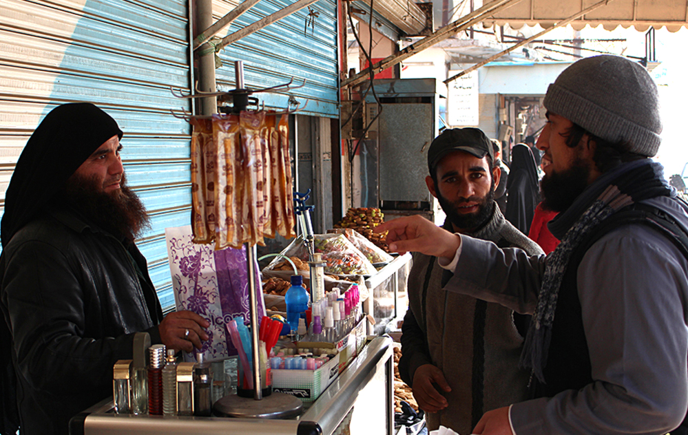A member of IS speaks with a perfume street vendor in Raqqa. (The Associated Press)