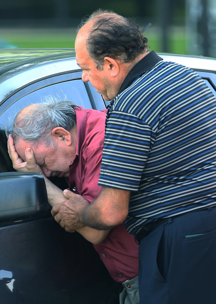 A man is comforted after finding out that a relative drowned in her truck in Houston on Tuesday. A holiday weekend of storms dumped record rainfall on the American heartland, causing major flooding.