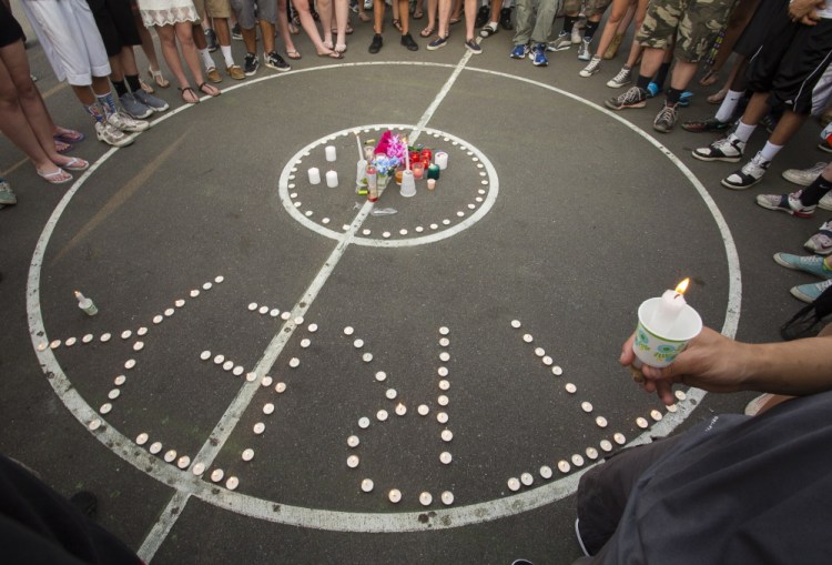 Mourners gather Tuesday evening around a memorial set up on a public basketball court off Main Street in downtown Westbrook where 19-year-old shooting victim Treyjon Arsenault was a regular.