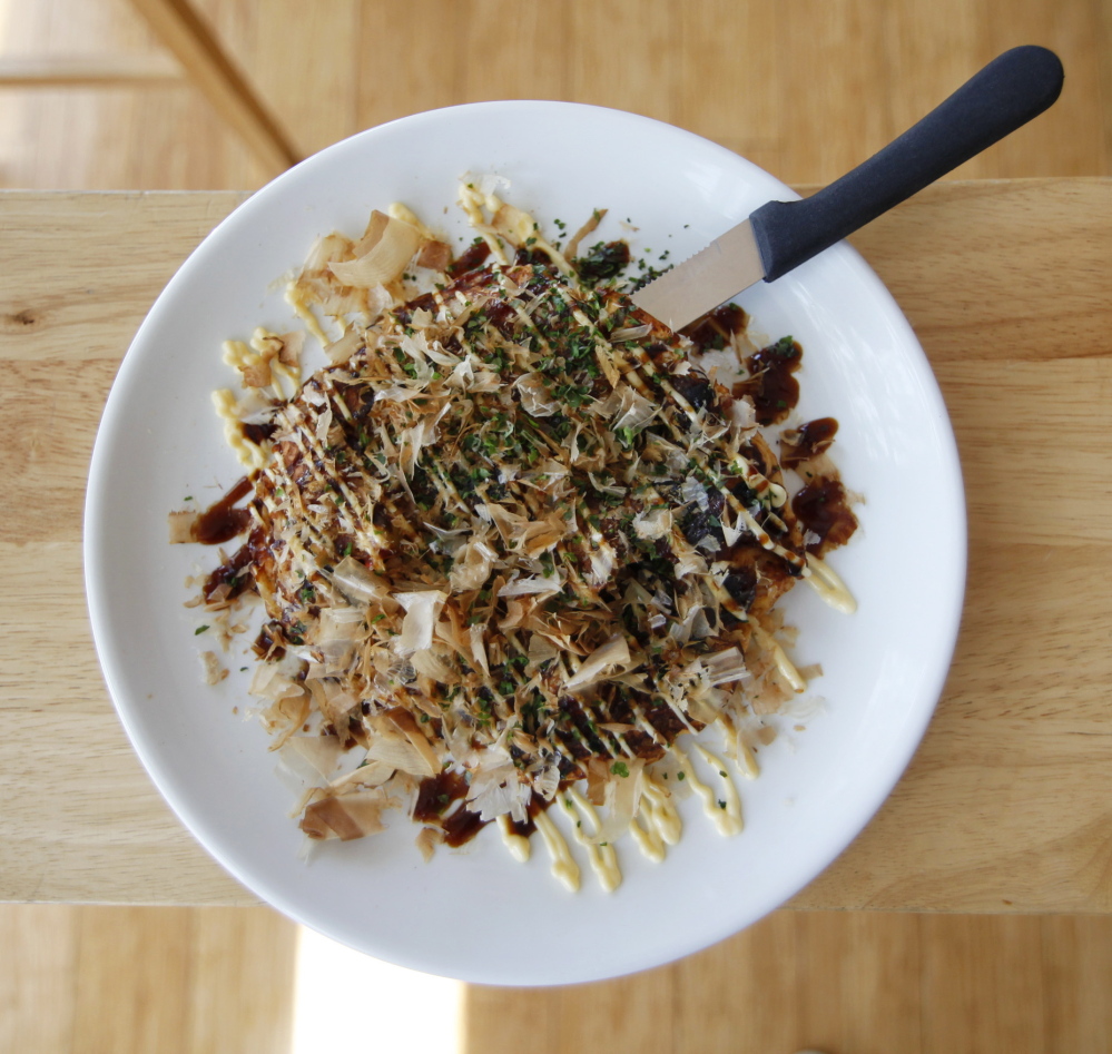A serving of okonomiyaki, a Japanese pancake topped with pork belly, shrimp, kimchi, sauce, kewpie mayo and bonito flakes. Jill Brady/Staff Photographer