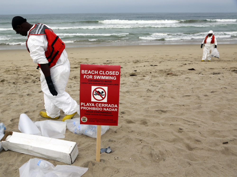 A cleanup crew collects small patches of tar that were washed ashore at Manhattan Beach, Calif., on Thursday. A seven-mile stretch has been closed as a health precaution.