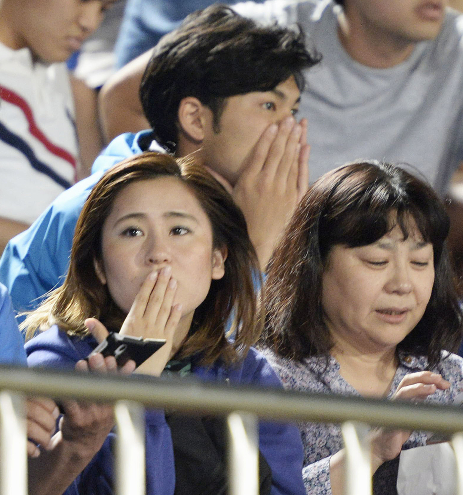 Japanese soccer fans react to a strong earthquake as they watch a J-League soccer match between the Shonan Bellmare and the Sanfrecce Hiroshima at BMW Stadium in Hiratsuka, southwest of Tokyo Saturday.