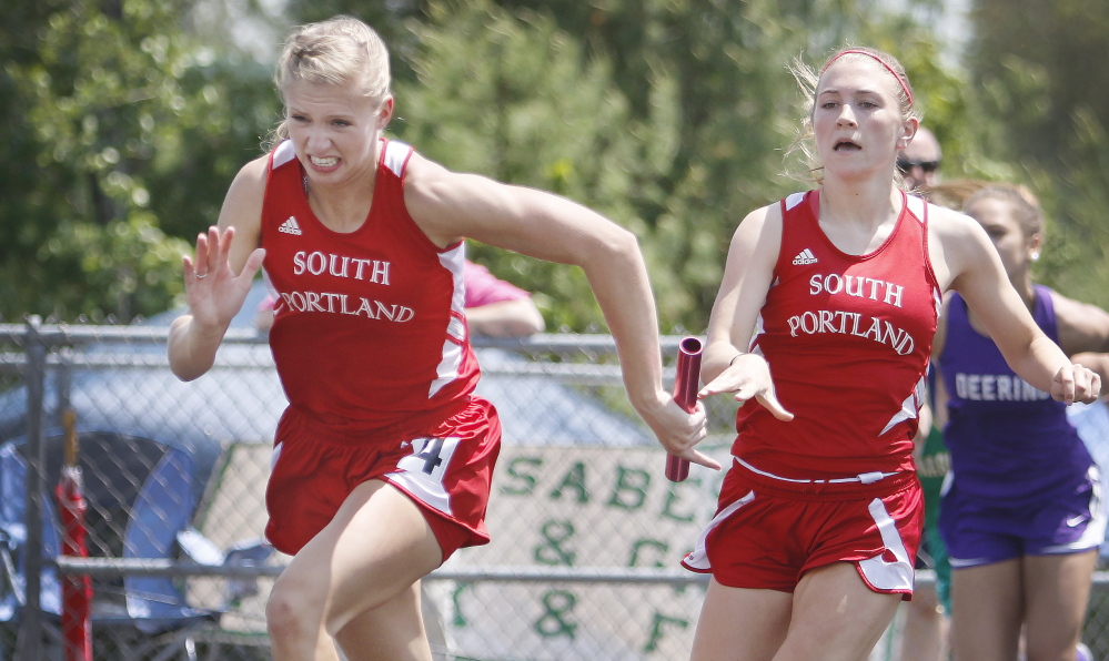 Callie O’Brien of South Portland, right, makes the handoff to teammate Lauren Magnusson during the 400-meter relay. South Portland was third in the girls’ meet, behind Thornton Academy and Scarborough.