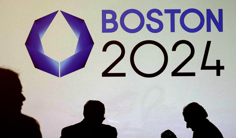 Shadows of organizers and reporters pass a video display screen prior to a January news conference by organizers of Boston’s campaign for the 2024 Summer Olympics in Boston.