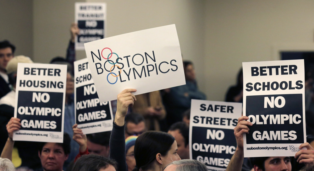 At a public forum in February, people hold up placards opposing Boston’s bid to host the Olympics in 2024. Verbal and online abuse has been used by proponents and foes.
