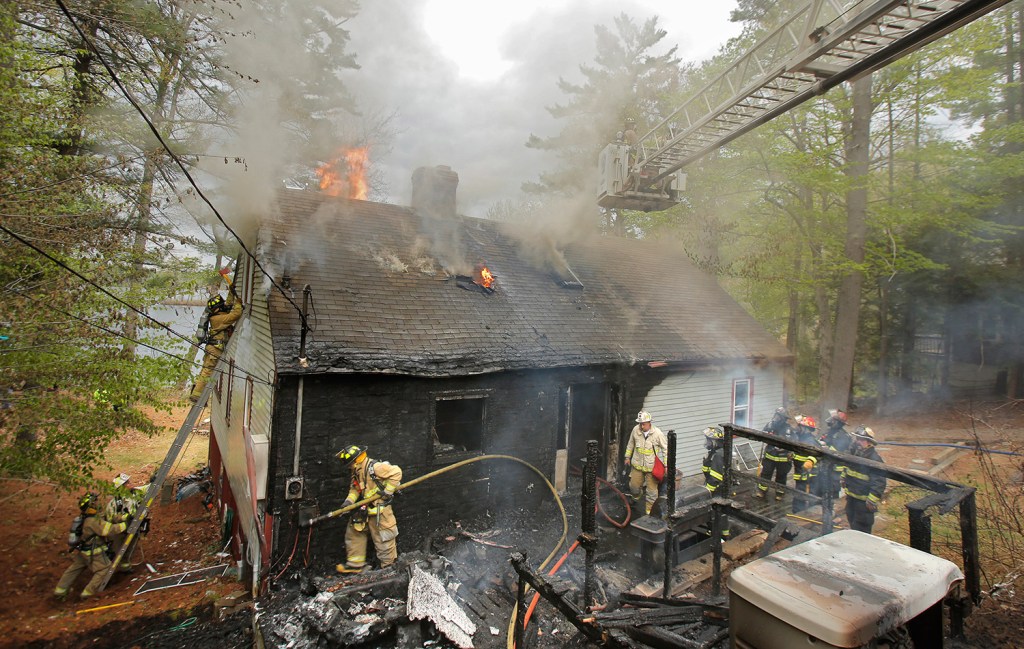 A firefighter moves a hose at a fire at a home on Bauneg Beg Pond in North Berwick on Tuesday. Firefighters from nine departments helped the North Berwick fire department douse the fire.
Gregory Rec/Staff Photographer