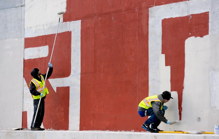 Tom Kane, left, and Caleb Lewis of Graffiti Busters work together to clean up graffiti on the Martin's Point Bridge in Falmouth. The program will receive an infusion of money from CBRE, a real estate company.