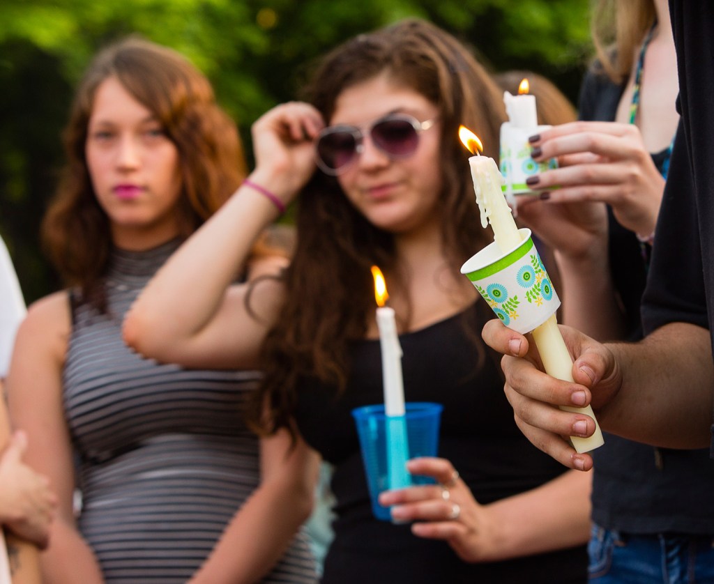 Mourners hold candles in memory of Treyjon Arsenault, a Westbrook High School graduate who was shot to death early Tuesday morning.