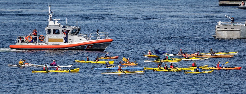 A small flotilla of kayakers protesting the oil drilling rig Polar Pioneer are followed by a U.S. Coast Guard boat in Elliott Bay in Seattle. The Associated Press