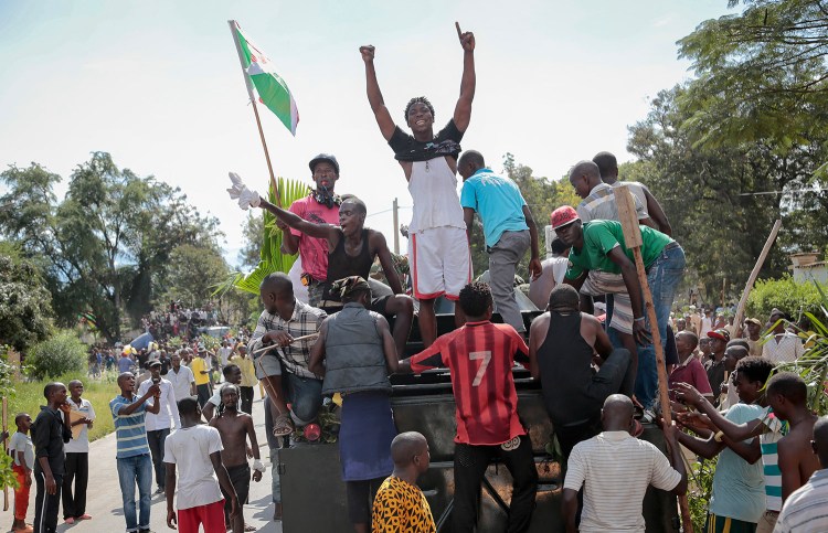 Demonstrators climb aboard a military truck as they celebrate what they perceive to be an attempted military coup d'etat, with army soldiers riding in an armored vehicle in the capital Bujumbura, Burundi Wednesday.