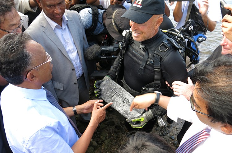 Underwater explorer Barry Clifford, right, presents a silver bar he believes is part of the treasure of the pirate Captain Kidd, to the president of Madagascar, Hery Rajaonarimampianina, left, on Sainte Marie Island, Madagascar. 