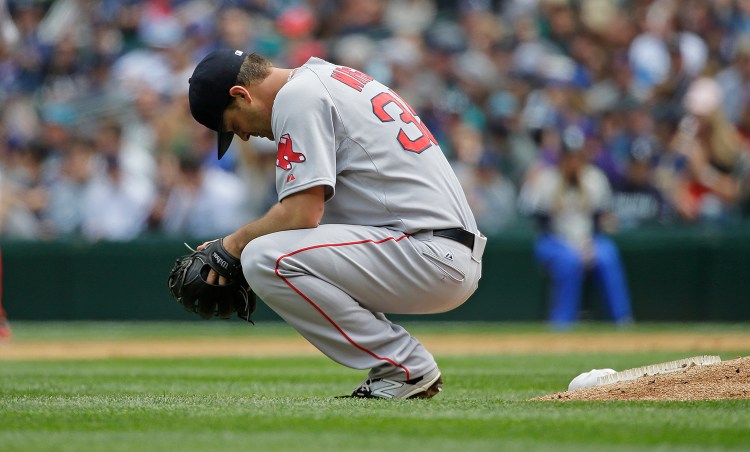 Boston Red Sox starting pitcher Steven Wright crouches near the mound during the third inning of a baseball game against the Seattle Mariners, Sunday, May 17, 2015, in Seattle. Wright picked up the loss as the Mariners defeated the Red Sox 5-0. (AP Photo/Ted S. Warren)