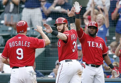 Texas Rangers Adam Rosales and Josh Hamilton are congratulated by Hanser Alberto, right, after scoring on a 2 RBI double hit by Robinson Chirinos in the fourth inning against the Boston Red Sox on Saturday, in Arlington, Texas. The Associated Press