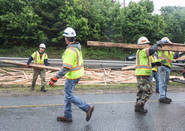 Workers clean up lumber in the median between the northbound and southbound lanes of Interstate 295 after a truck spilled its contents Monday afternoon. No one was injured in the crash, but traffic was reduced to one lane in both directions.