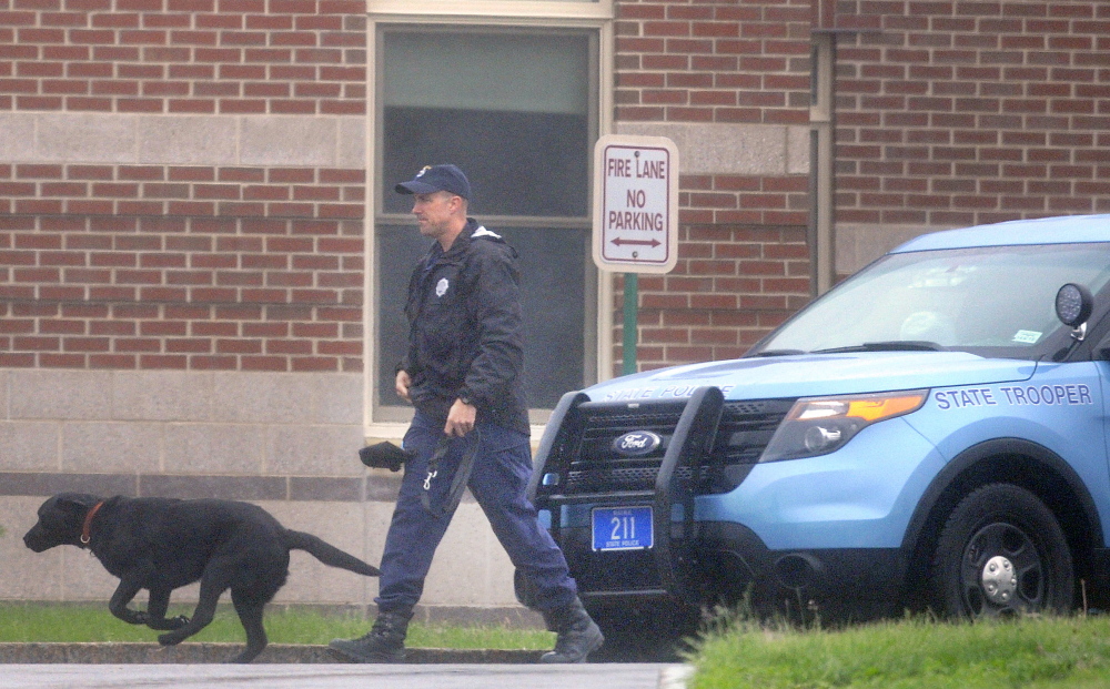 A state trooper escorts a police dog Tuesday around the exterior of Cony High School in Augusta after an evacuation because of a threat.