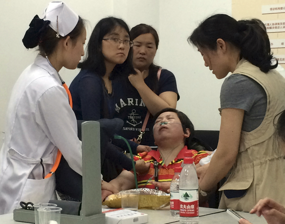 A relative of Shanghai passengers on board a cruise ship that capsized in central China, is attended to by a medical worker as she waits for answers at a government office in Shanghai, China, Tuesday.