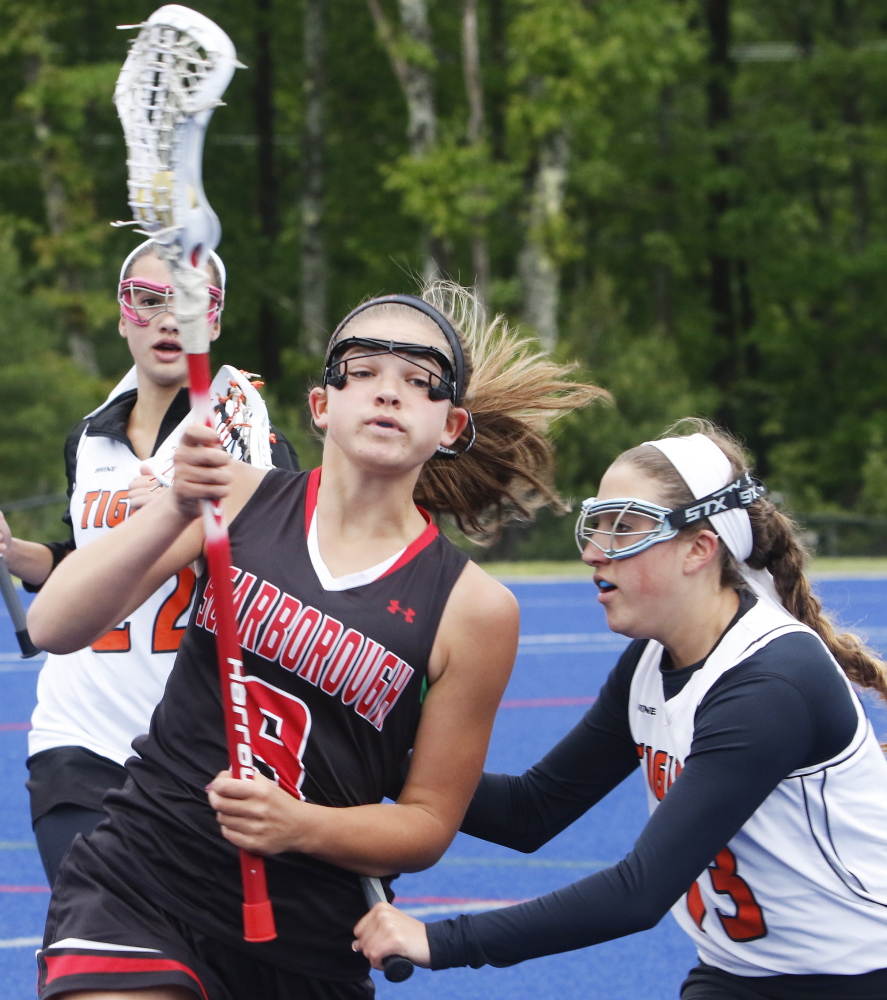 Maddie York of Scarborough looks for a way to advance while defended by Missy Huot of Biddeford in the first half.