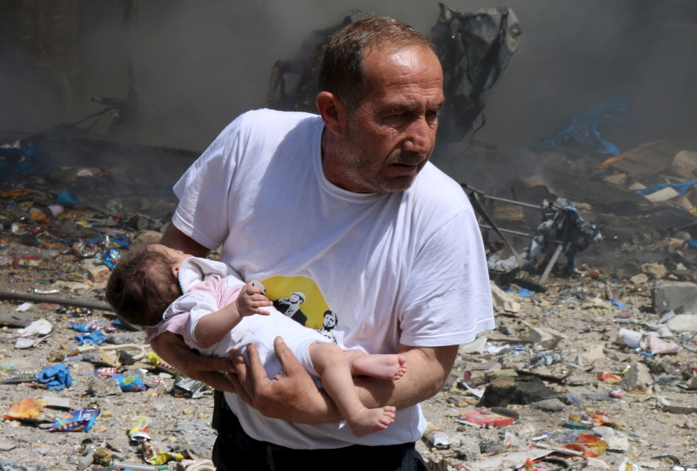 A man holds a baby that survived what activists said was a barrel bomb dropped in Aleppo by forces loyal to Syria’s president.