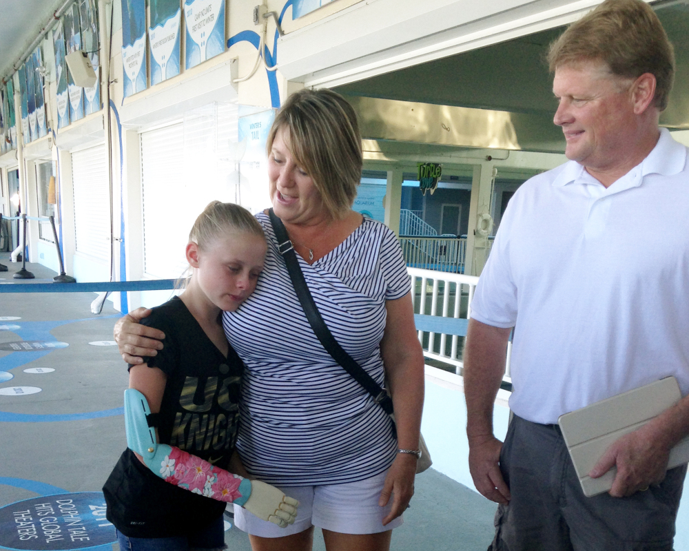 Annika Emmert, left, a 10-year-old who was born without part her right arm, wears her new arm as she stands with her parents.