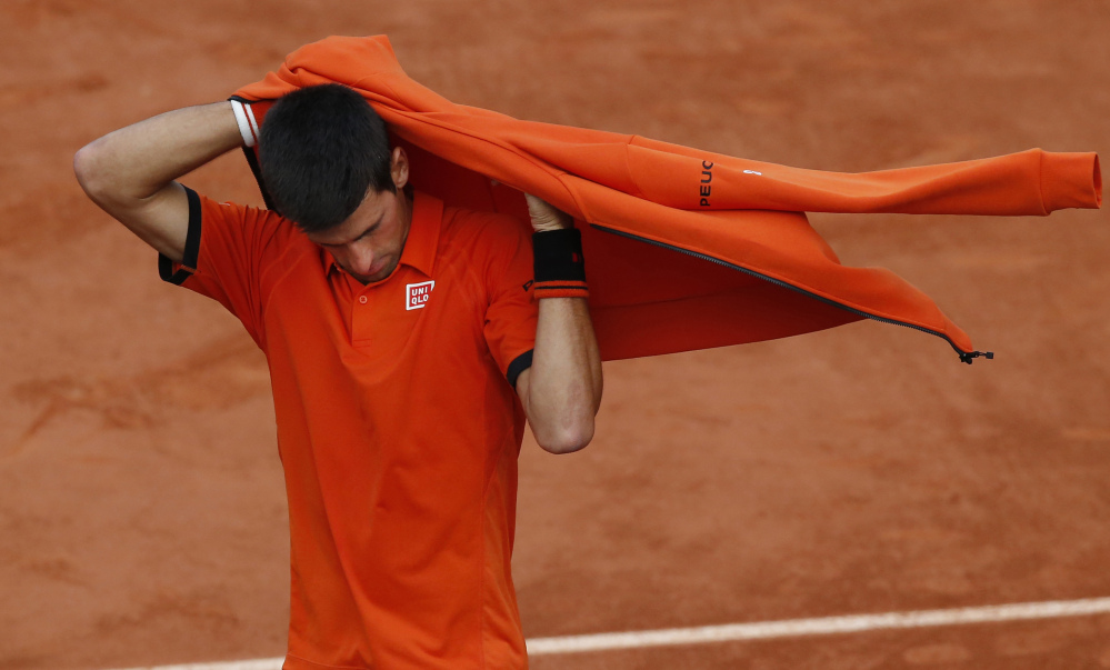 Serbia’s Novak Djokovic puts on his jacket after imminent thunderstorms forced officials to interrupt the semifinal match of the French Open tennis tournament against Britain’s Andy Murray at the Roland Garros stadium in Paris, France, on Friday.