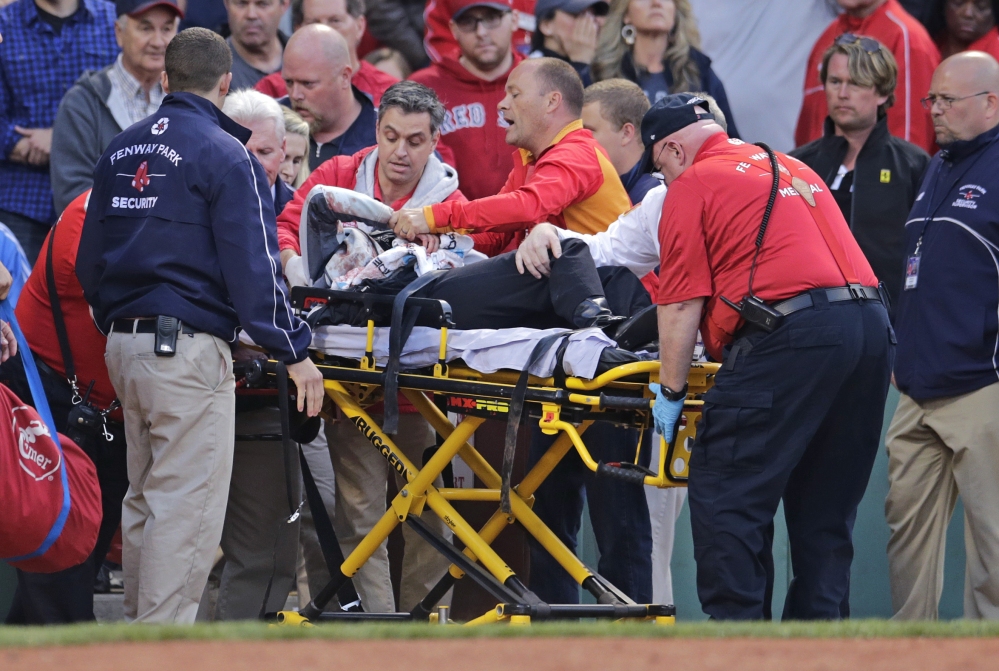 A fan who was hit on the head with a broken bat is taken from the stands Friday night at Fenway Park. The game stopped and the woman was wheeled out to be taken to a hospital.