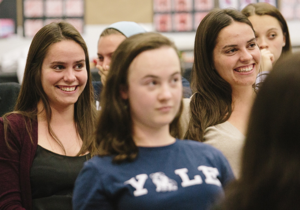 Above: Tess Hinchman, right, and twin sister Abbie sit for graduation practice at North Yarmouth Academy on Tuesday. Right: Olivia Stam, back right, and her twin sister Marina laugh with classmates gathering for a photo.
