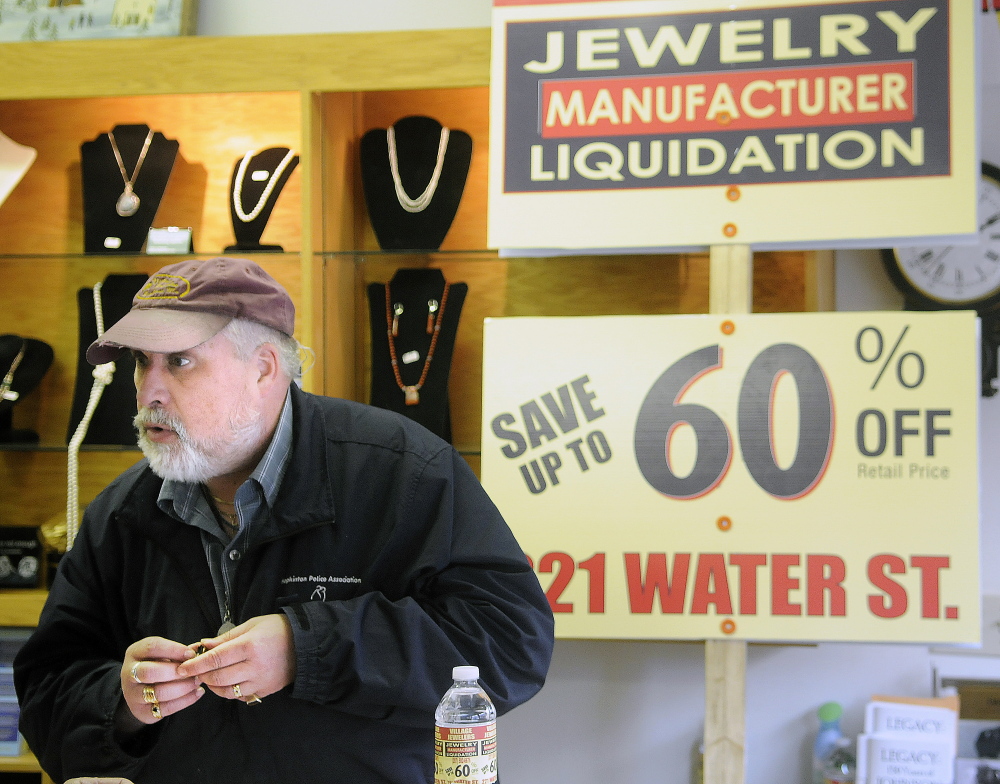Above, a sign for a discount sale at The Village Jeweler store sits on the street in front of the business in Gardiner. State officials have told owner Daniel Lane to stop using sign walkers to advertise a liquidation sale.
Below, Lane appraises a ring in front of a sign that officials told him to stop using off-premises.