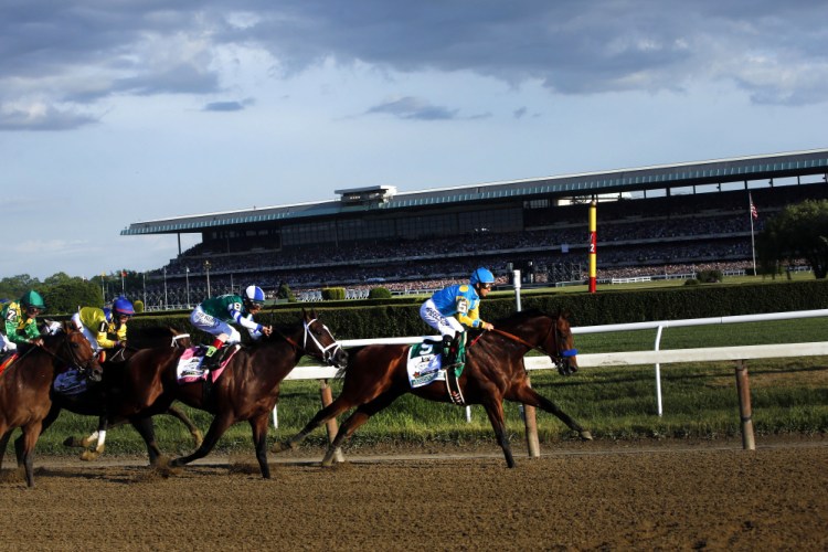 American Pharoah (5) leads the field entering turn three on the way to a Triple Crown victory during the 147th running of the Belmont Stakes at Belmont Park on Saturday in Elmont, N.Y.