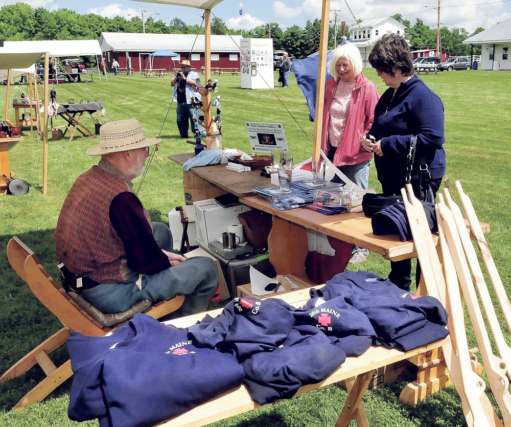Gary Moore speaks with Sue McLaughlin, center, and Jill Low at a Civil War store set up Saturday during a reenactment in Clinton.