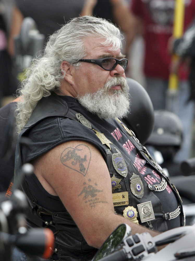Mark Gauthier of Gilford watches the scene at Weirs Beach wearing a variety of police badges on his vest, during bike week in Laconia, N.H., in 2010.