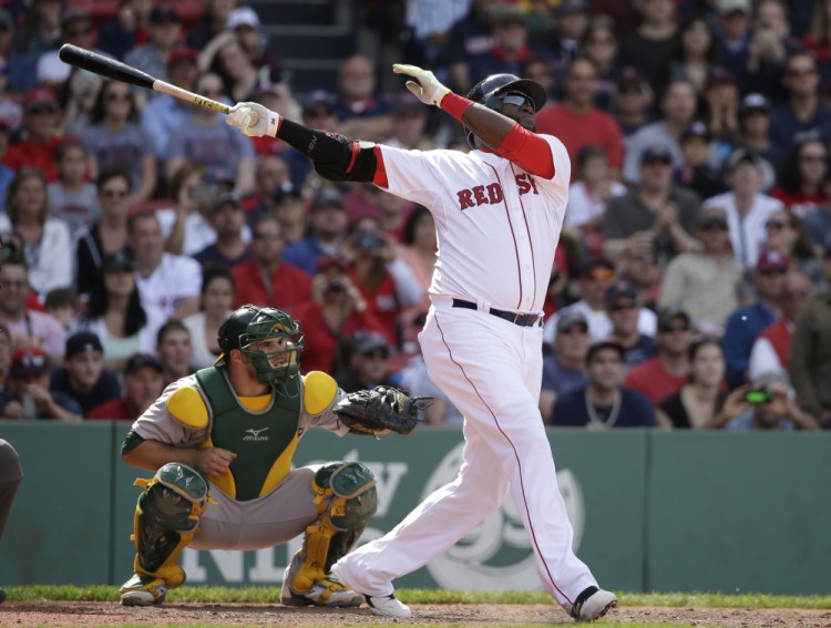 Boston Red Sox designated hitter David Ortiz hits a sacrifice fly, allowing Brock Holt to score in the eighth inning against Oakland Sunday in Boston.