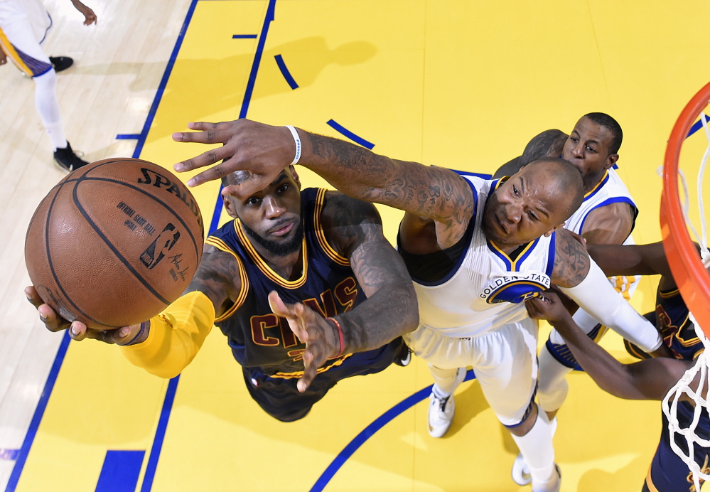 Cleveland’s LeBron James goes up for a shot against Marreese Speights of the Golden State Warriors during Game 2 of the NBA finals Sunday in Oakland, Calif. James scored 39 points, and the Cavaliers tied the series with a 95-93 overtime win.