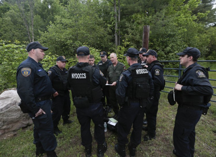 State forest ranger Dan Fox reviews a map with members of the New York State Department of Corrections and Community Supervision emergency response team before entering a wooded area in search of two prisoners who escaped from the Clinton Correctional Facility on Monday in Dannemora, N.Y.