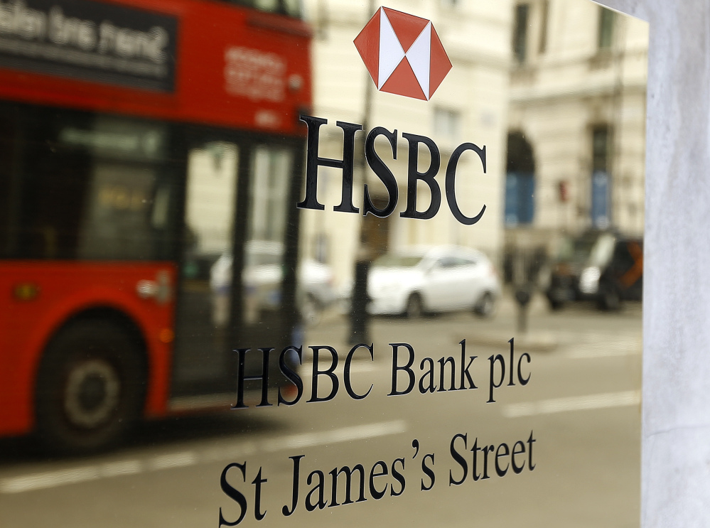 A London bus is reflected as it drives past an HSBC plaque in St James’s Street in London, Tuesday, June 9, 2015.